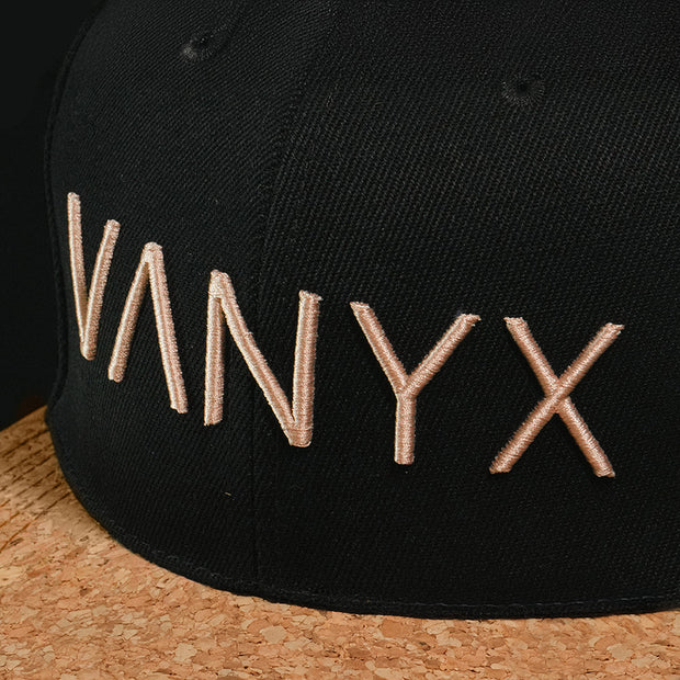 Nahaufnahme der Vanyx Cap mit gesticktem Logo auf schwarzem Stoff und Korkschirm