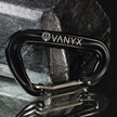 Schwarzer Vanyx Karabiner aus Aluminium mit Logo – liegend auf Stein